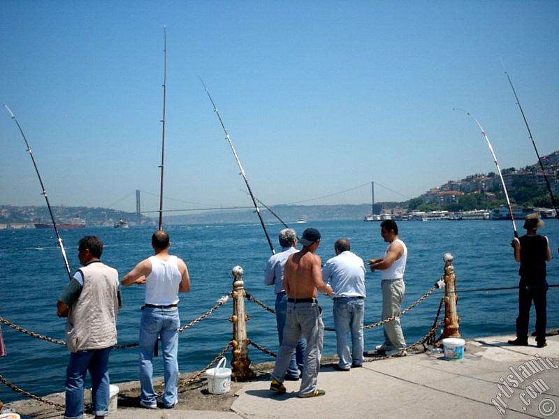 View of fishing people and on the horizon Bosphorus Bridge from Uskudar shore of Istanbul city of Turkey.
